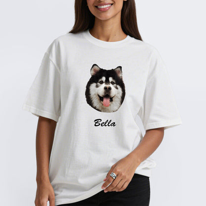 Person wearing a white custom pet t-shirt with a dog's face and name 'Bella' on a plain background