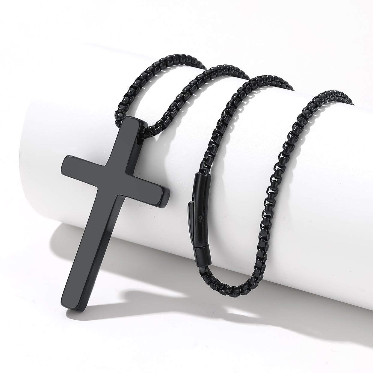 Black cross pendant necklace and bracelet on a white background