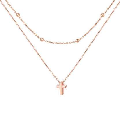 Rose gold cross necklace on a white background