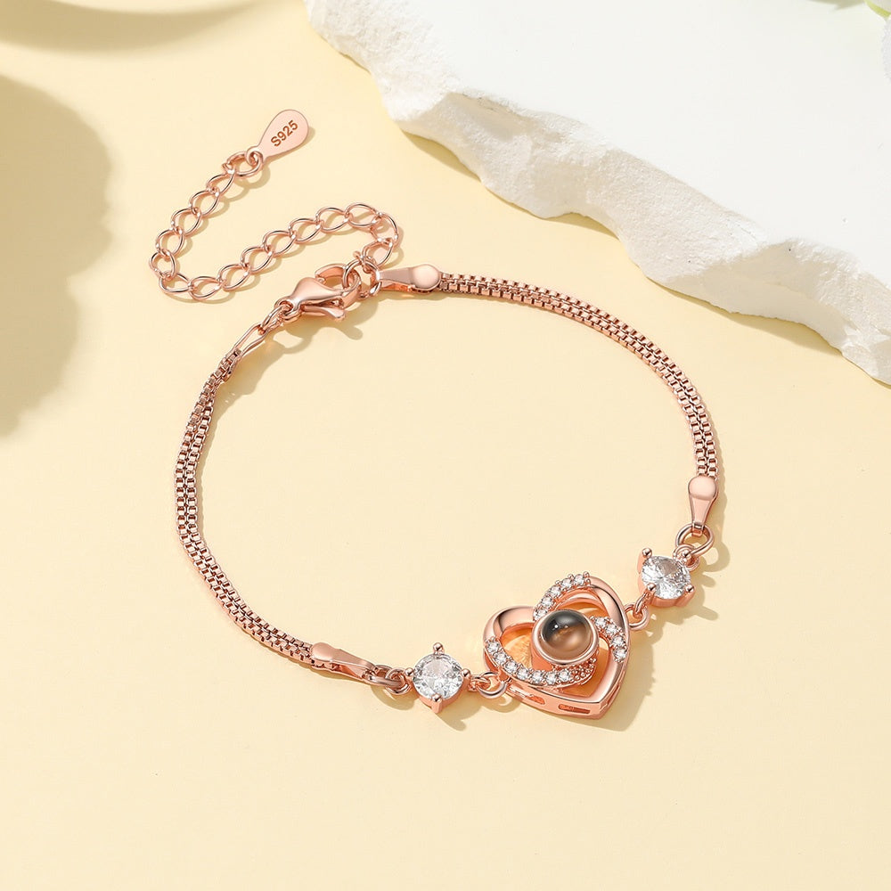 Rose gold heart photo bracelet with heart-shaped charm on a light yellow background