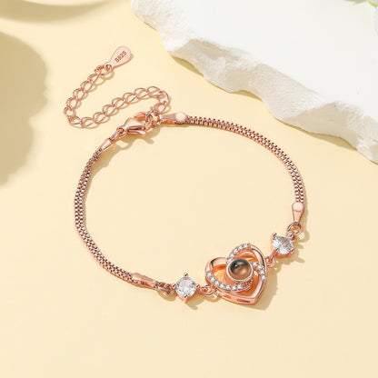 Rose gold heart photo bracelet with heart-shaped charm on a light yellow background