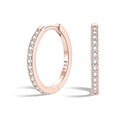 Rose gold huggie hoop earrings with embedded diamonds on a white background