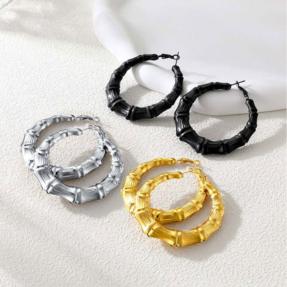 Set of bamboo hoop earrings in black, gold, and silver on a light background
