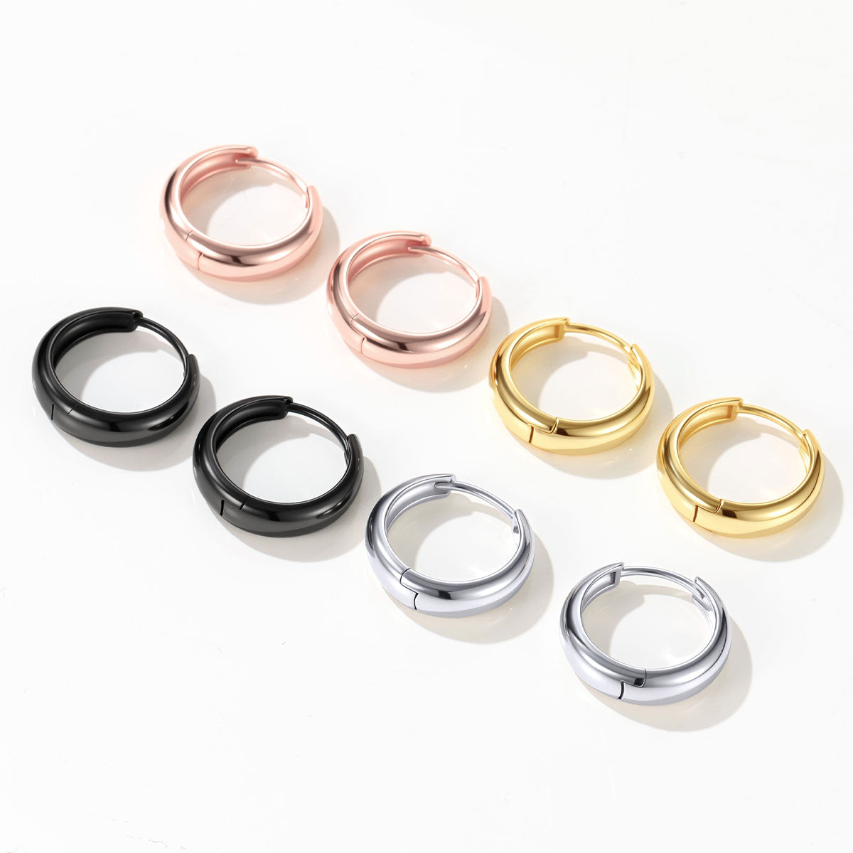 Set of chunky huggie earrings in various colors on a white background