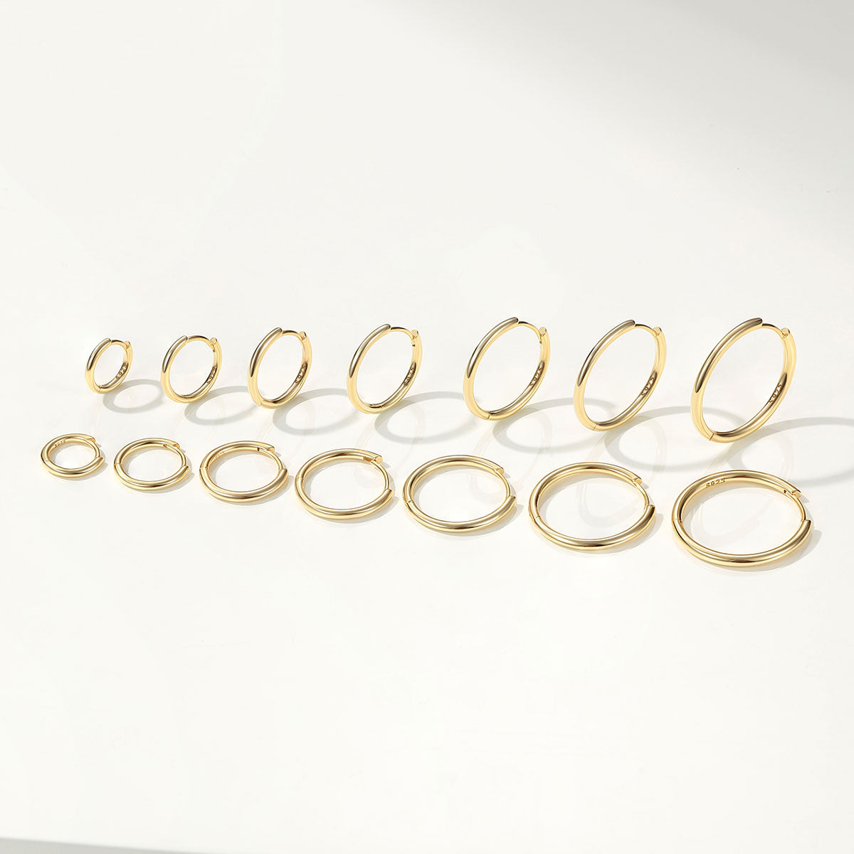 Set of gold huggie earrings on a white background