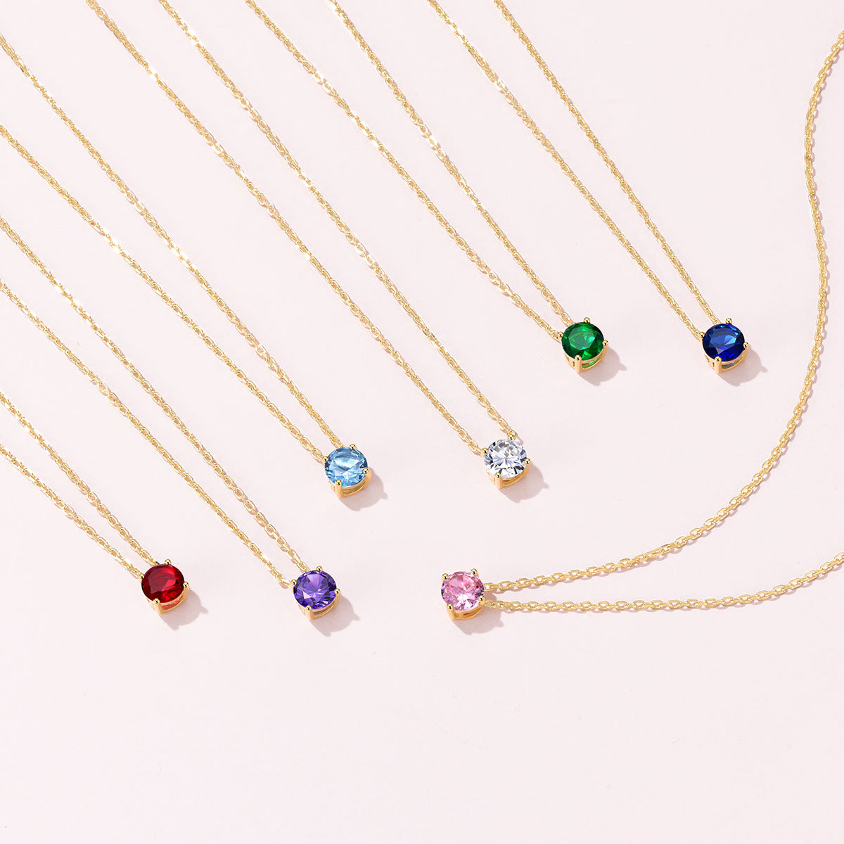 Seven Solitaire Birthstone Necklace on a pink background