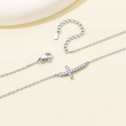 Silver Dainty Cubic Zirconia Sideways Cross Necklace for Women on a light yellow background