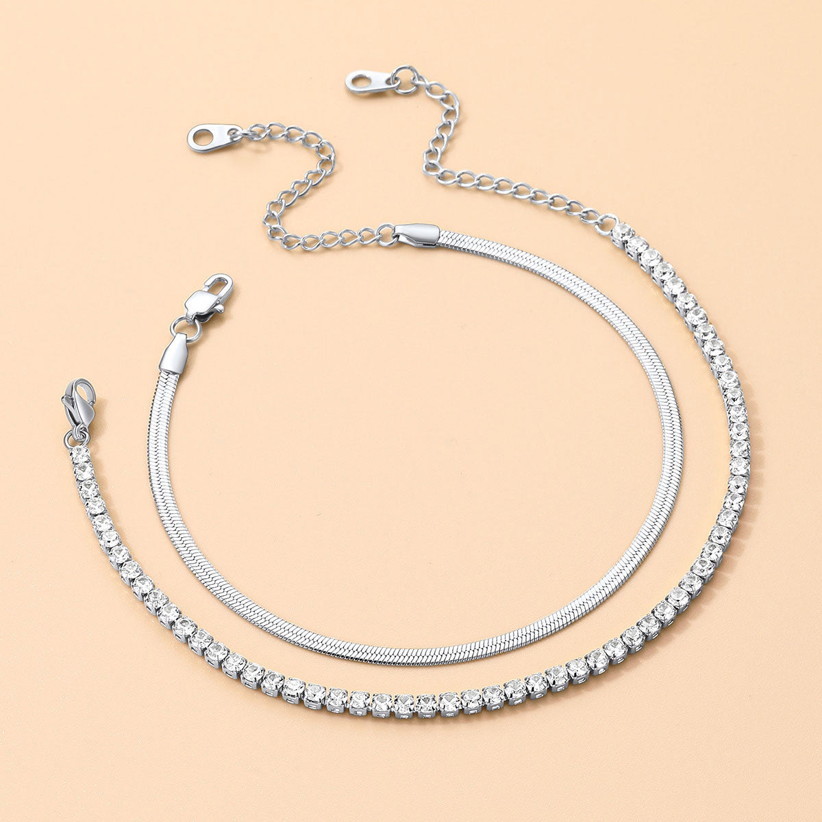 Silver chain ankle bracelet with clear stones on a beige background