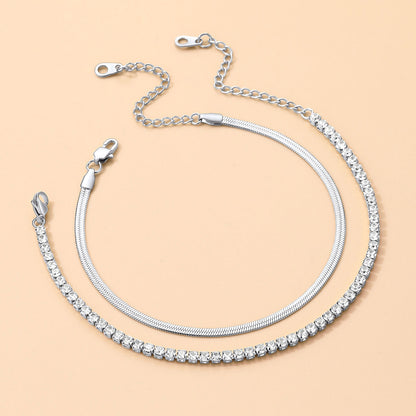 Silver chain ankle bracelet with clear stones on a beige background