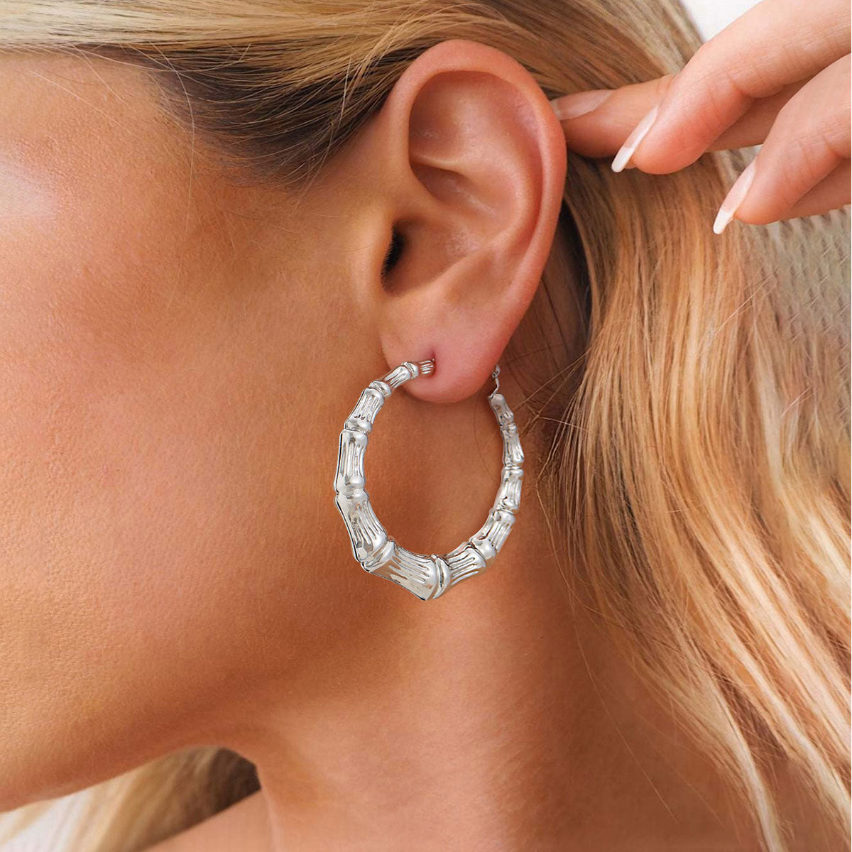 Silver chunky hoop earring worn by a person with blonde hair.