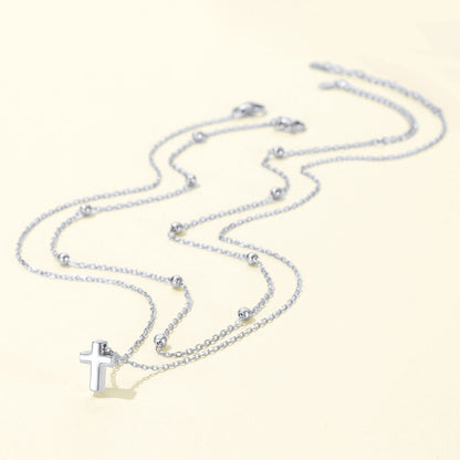 Silver cross necklace with a cross pendant on a light beige background