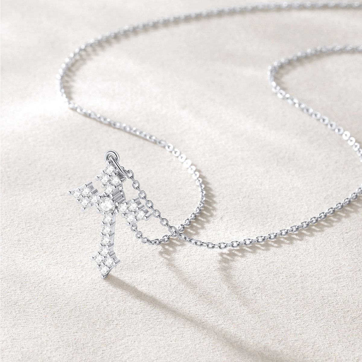 Silver cross necklace with a star-shaped pendant on a light beige background