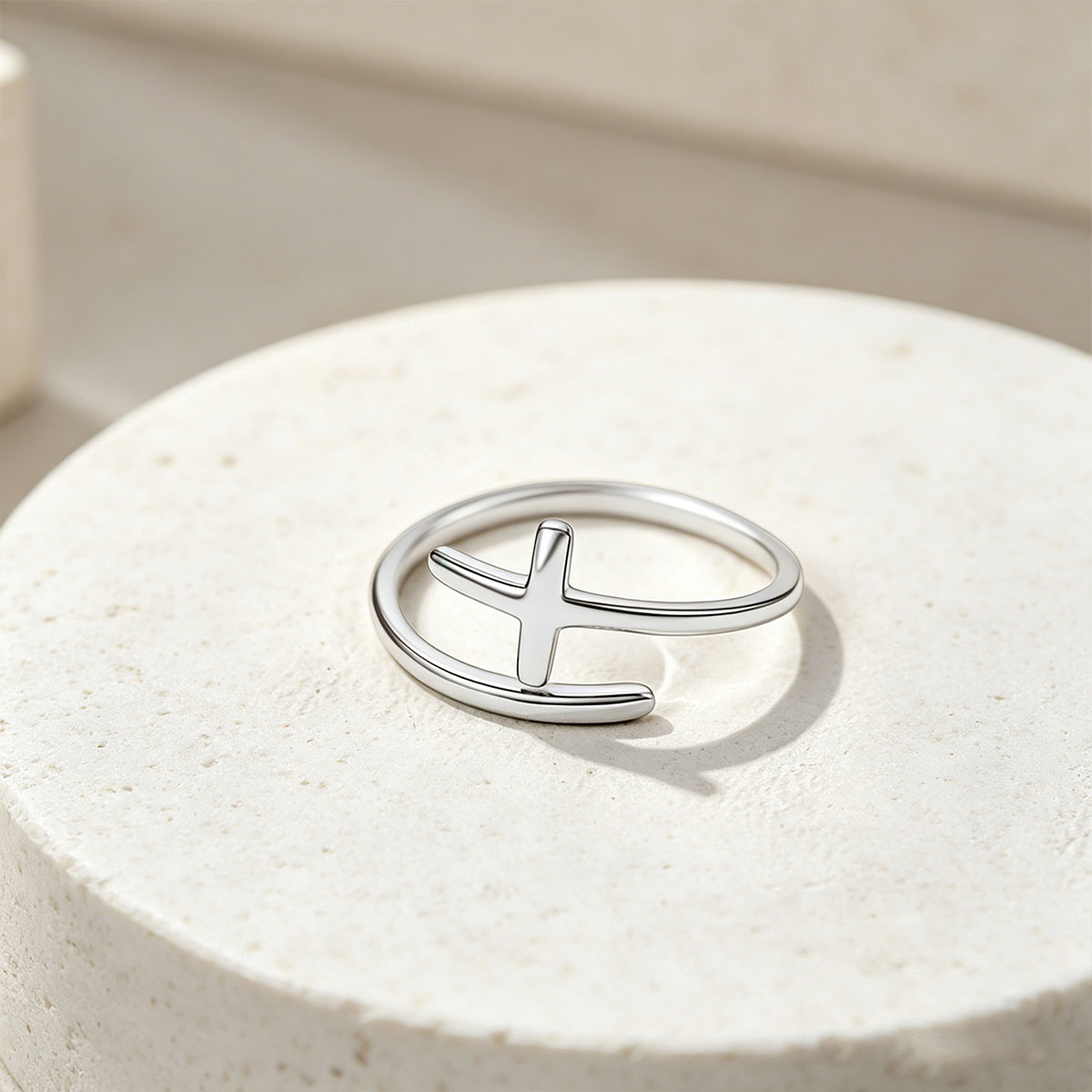 Silver cross ring on a light stone surface