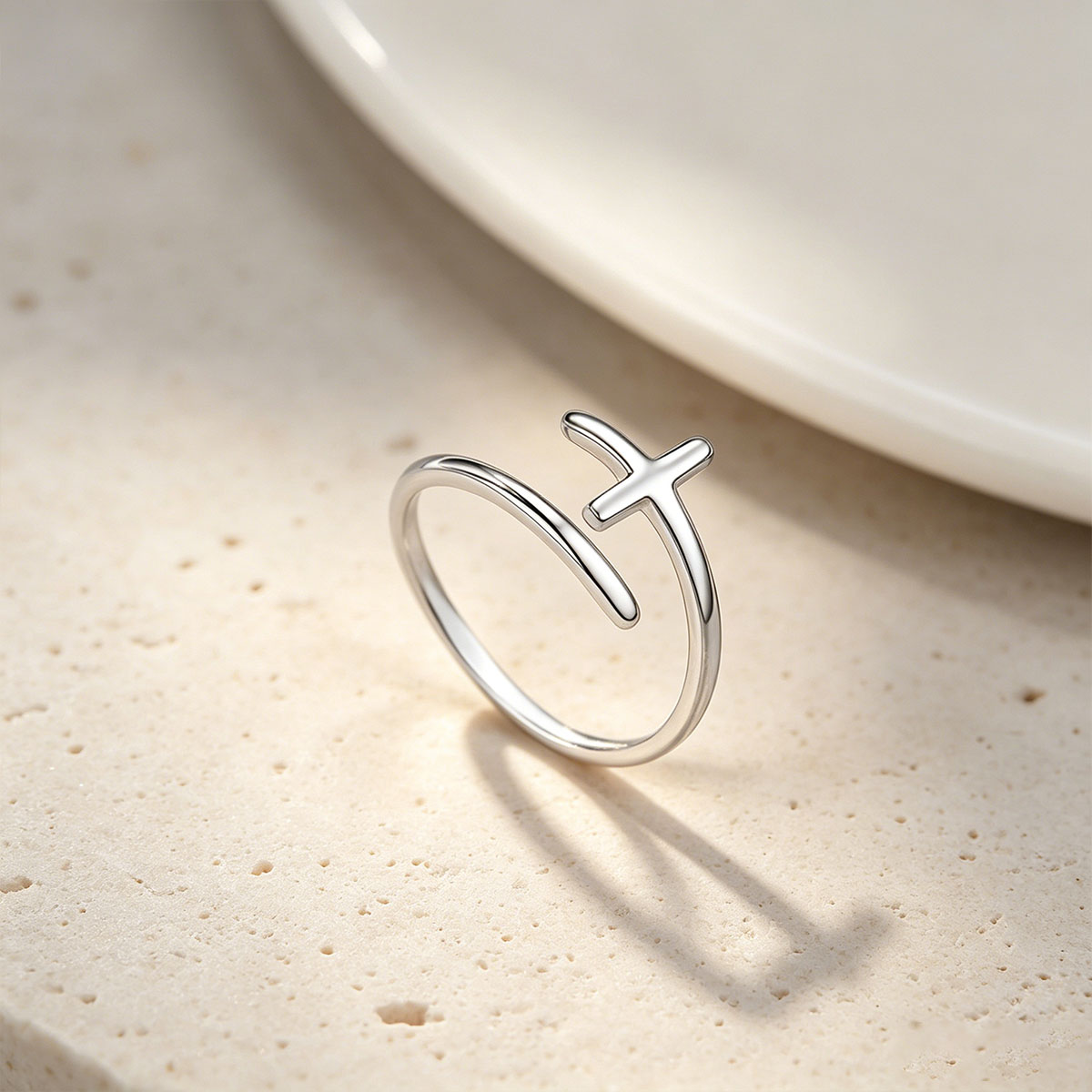 Silver cross ring with a unique design on a beige surface