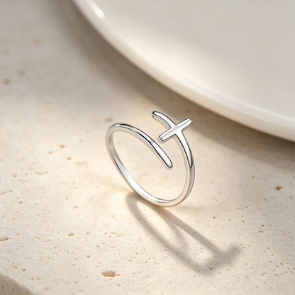 Silver cross ring with a unique design on a beige surface