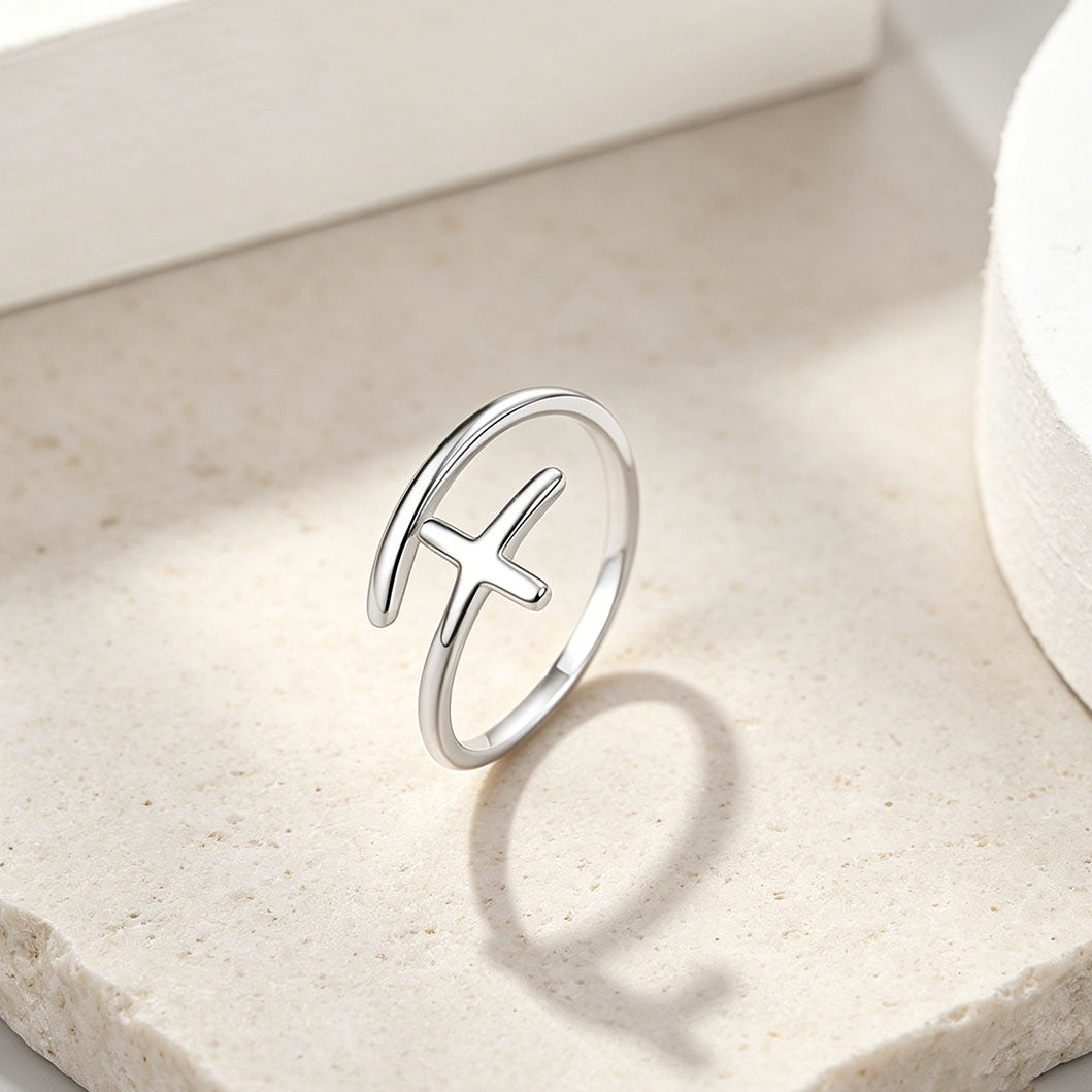 Silver cross ring with a unique design on a light beige surface