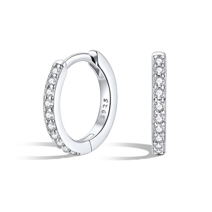 Silver cz huggie earrings with embedded stones on a white background