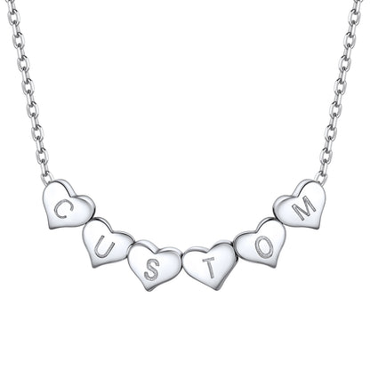 Silver heart initial necklace with heart-shaped charms spelling 'CUSTOM' on a white background