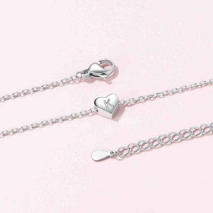 Silver heart necklace with lobster clasp on a light pink background