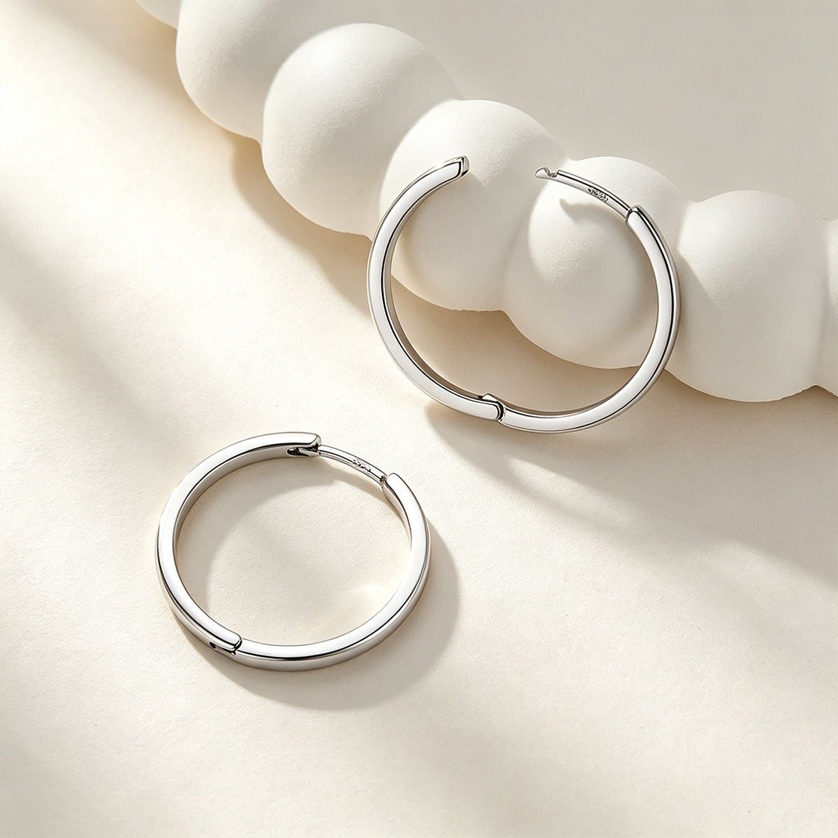 Silver hoop earrings on a light beige background