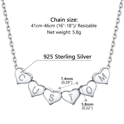Silver initial heart charm necklace with heart-shaped pendants displaying letters, chain size, and material information on a white background.