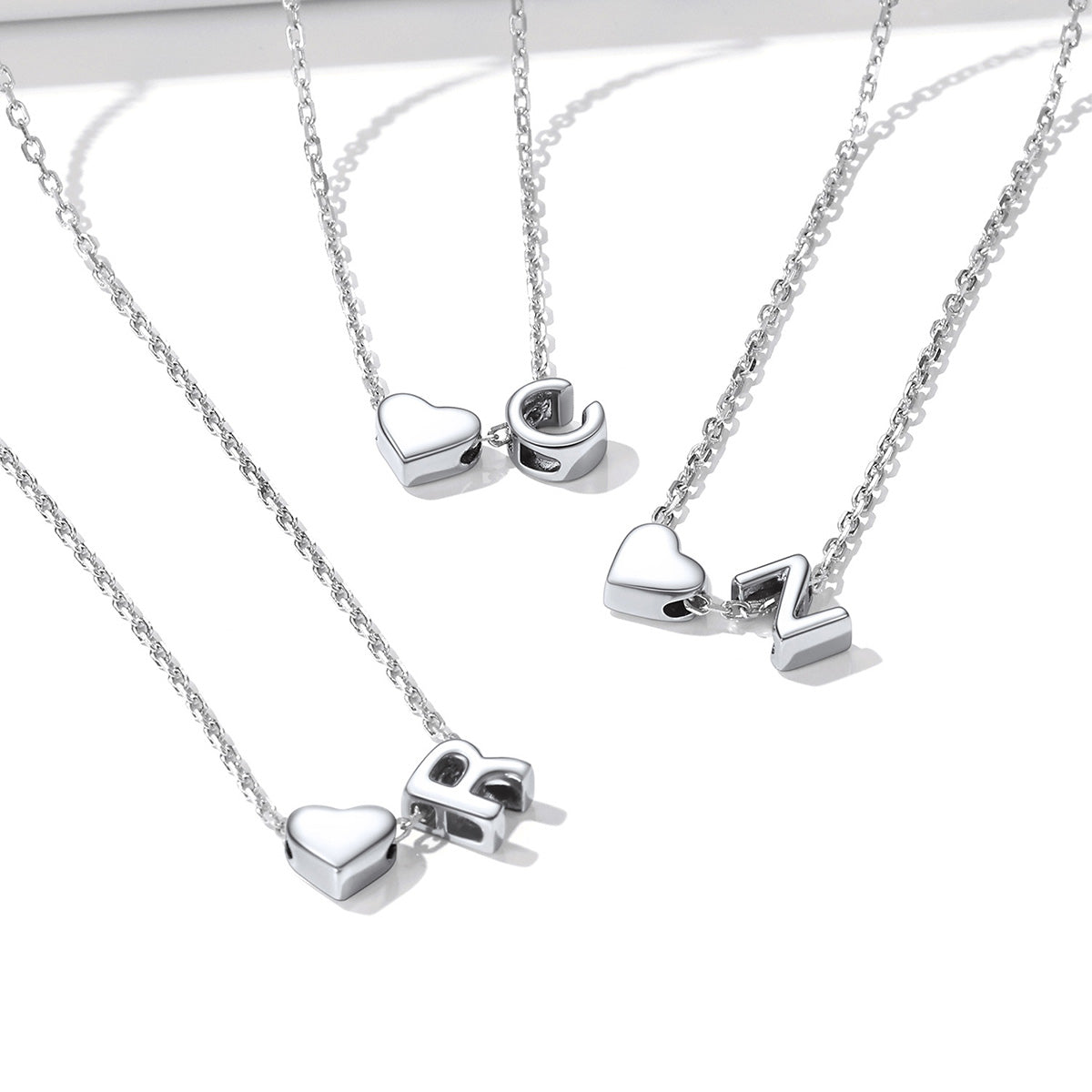 Silver initial heart necklaces with heart-shaped pendants 