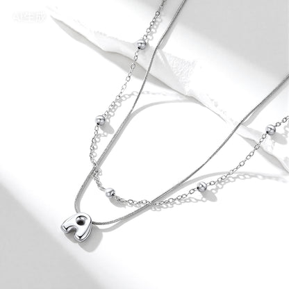 Silver initial layered necklace with a heart pendant on a white background