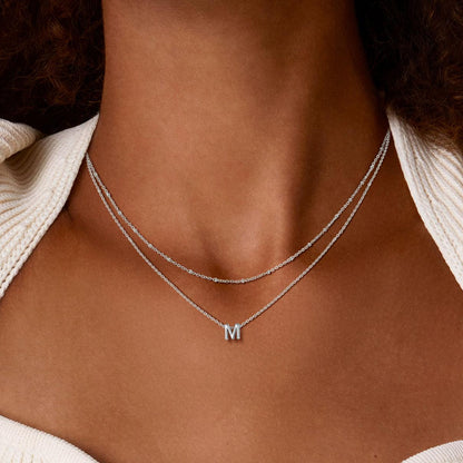 Silver initial necklace with a 'M' pendant on a white background