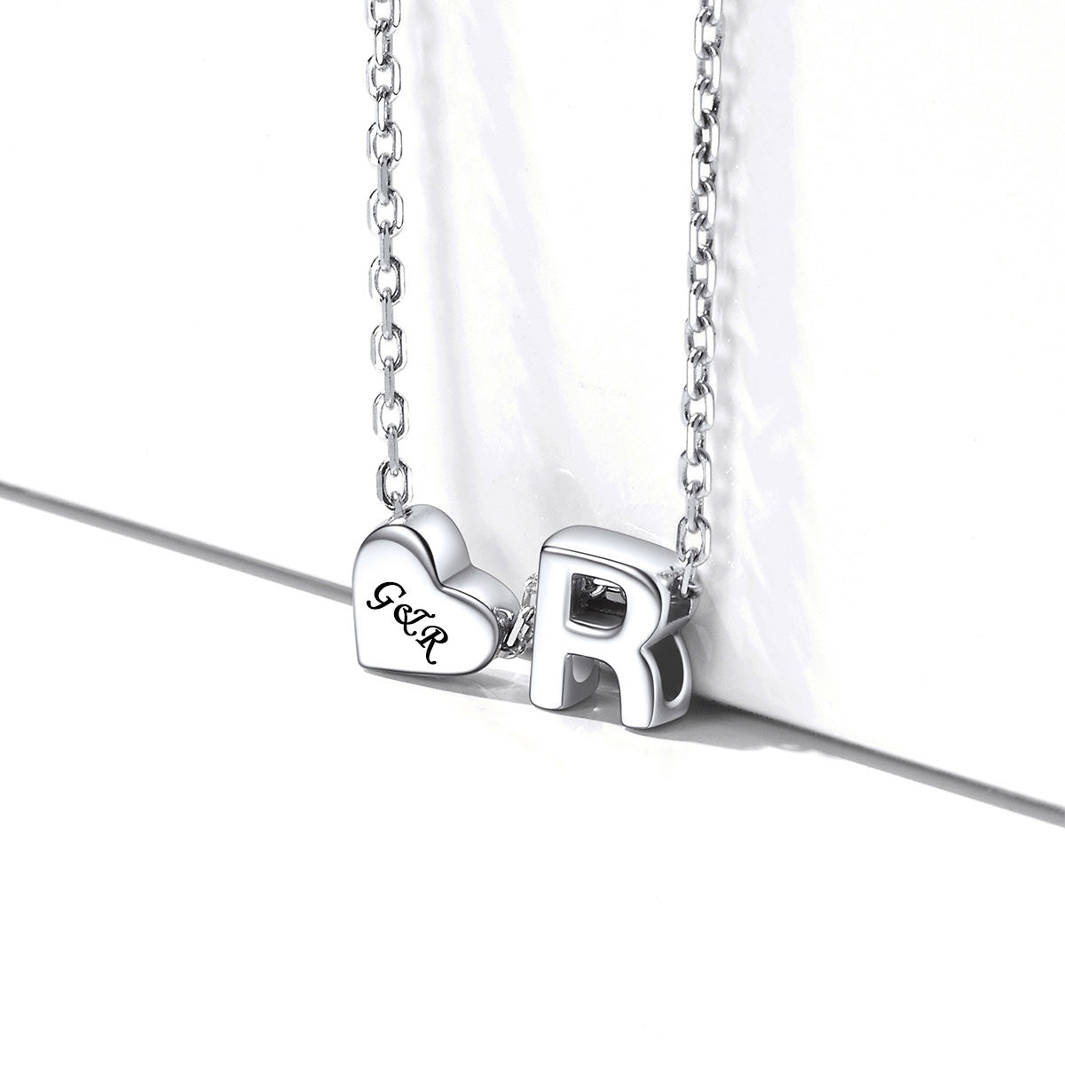Silver necklace with heart-shaped pendant and letter 'R'
