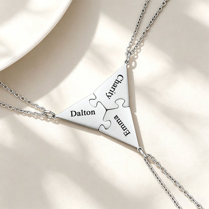 Silver puzzle matching necklace with engraved names on a beige background