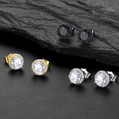Six pairs of CZ Halo stud earrings arranged on a dark textured surface, including black, yellow gold, silver, and clear stone settings, with a dark slate prop in the background.