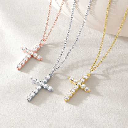 Three cross-shaped necklaces in rose gold, silver, and gold on a light background