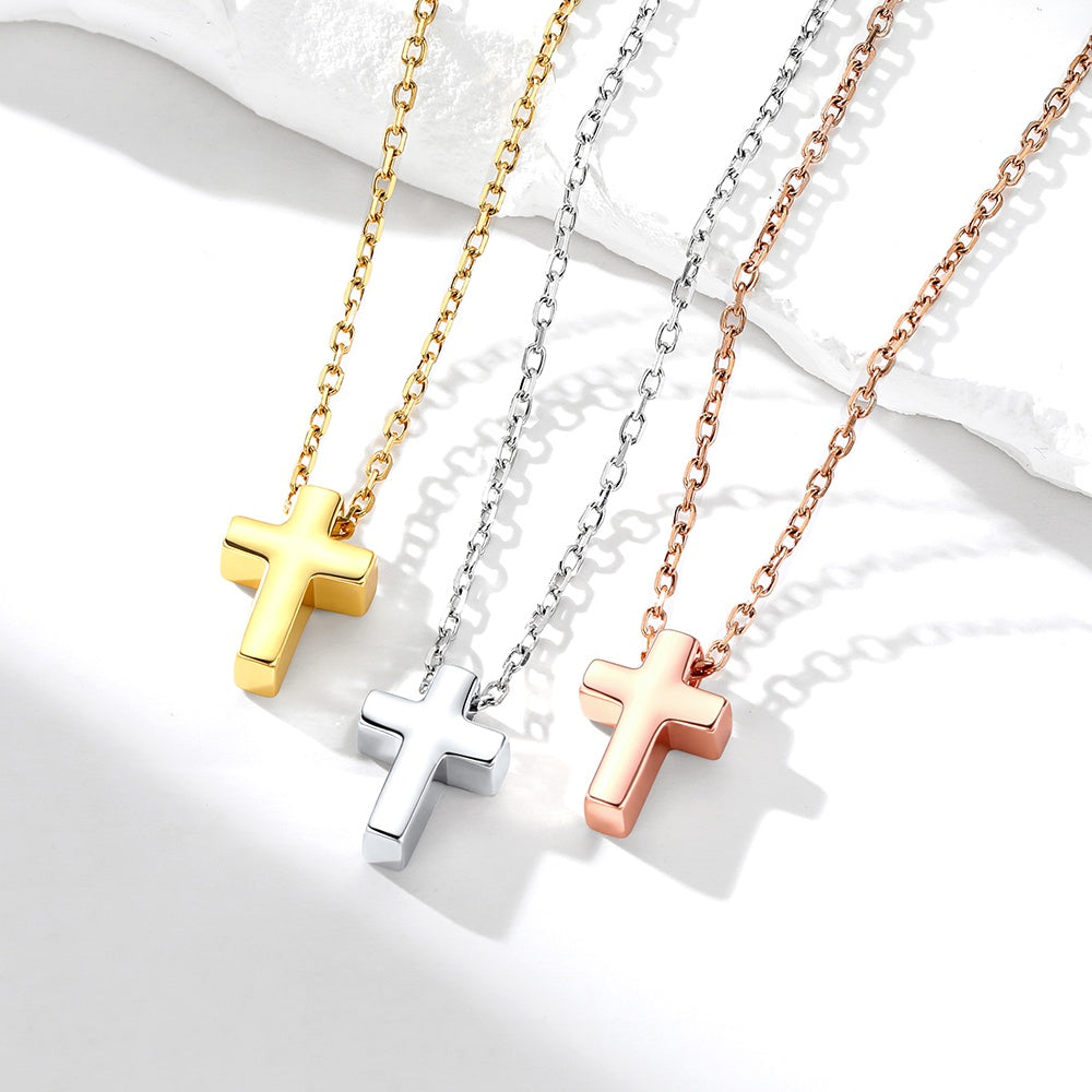 Three cross necklaces in gold, silver, and rose gold on a white background