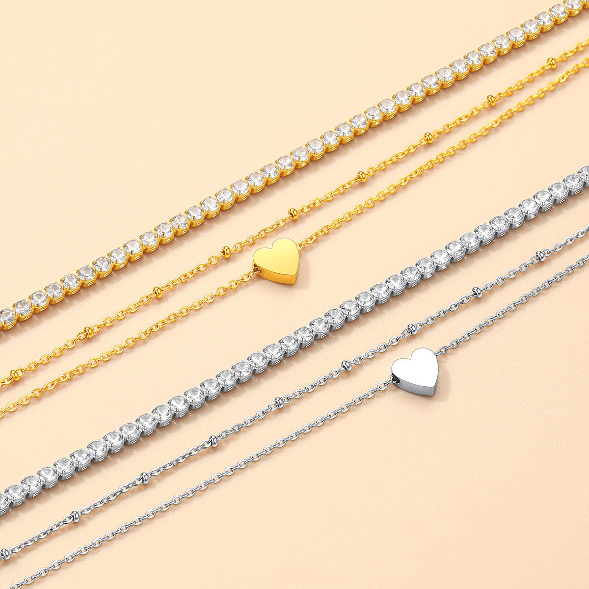 Three gold and silver heart-shaped anklets on a beige background