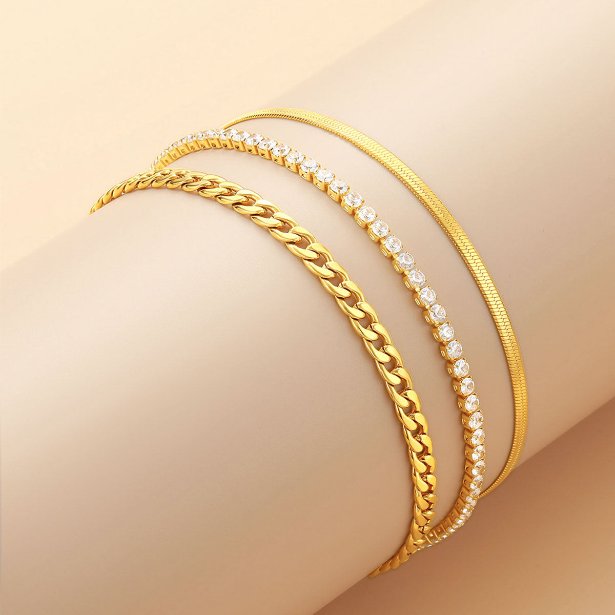 Three gold anklet on a beige surface