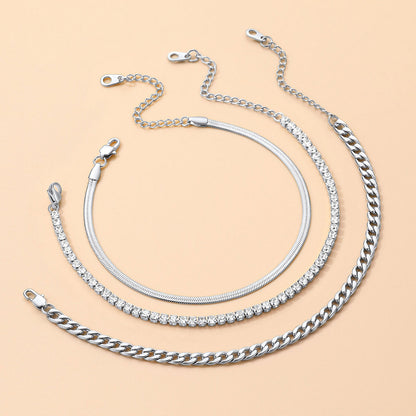 Three silver chain anklet of different styles on a beige background