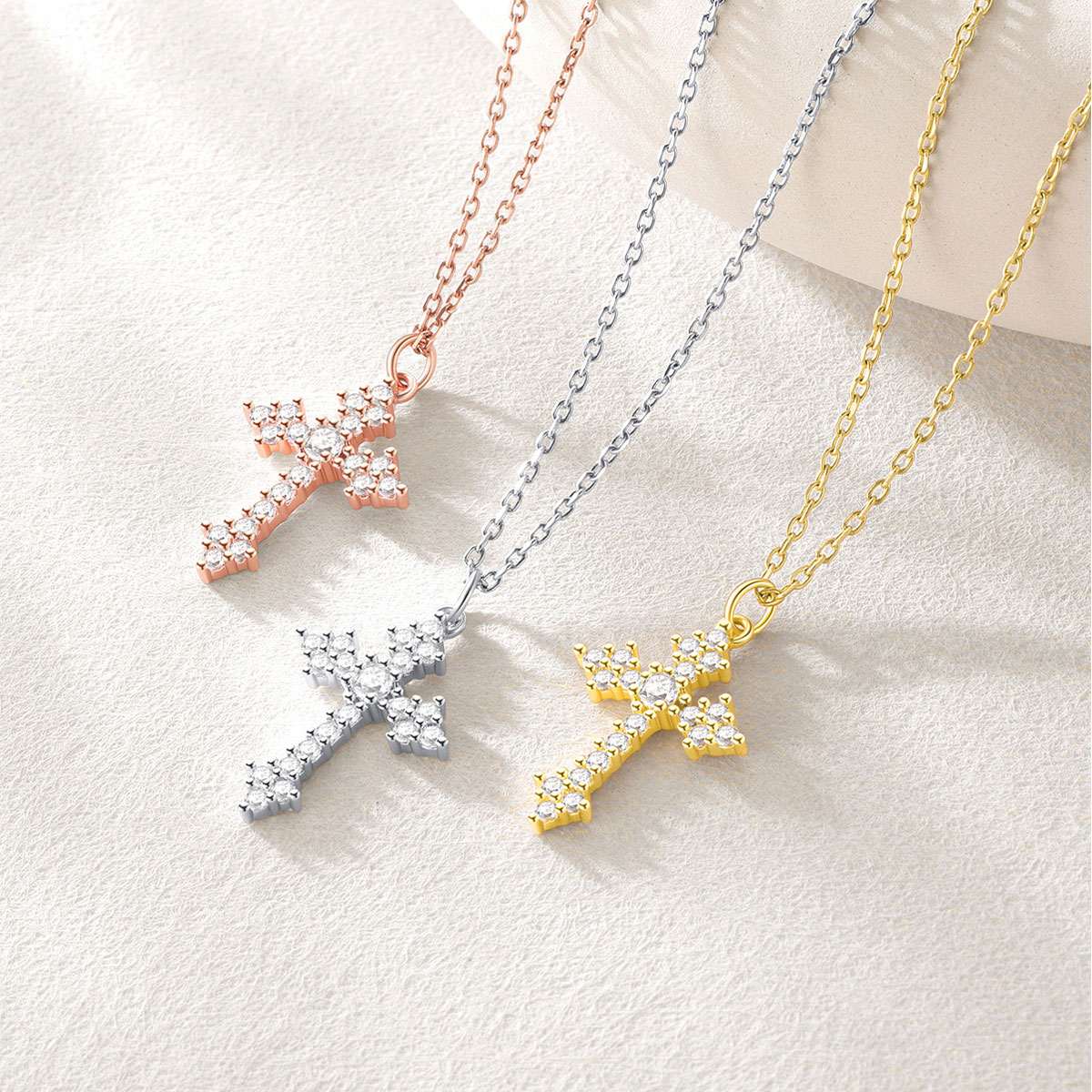 Three star-shaped necklaces in gold, silver, and rose gold on a light background