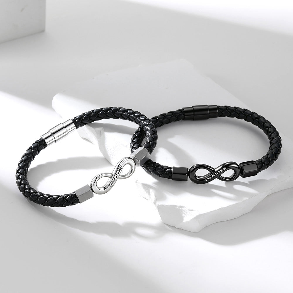 Two black braided leather infinity bracelets with infinity-shaped metal clasp details, displayed on a white surface with soft shadows.