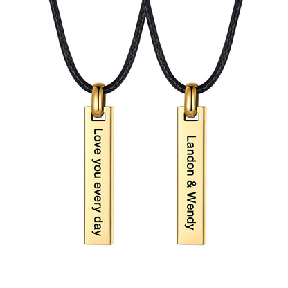 Two gold rectangular engraved bar pendant necklace on black cords, each engraved with personalized text, shown on a plain white background.