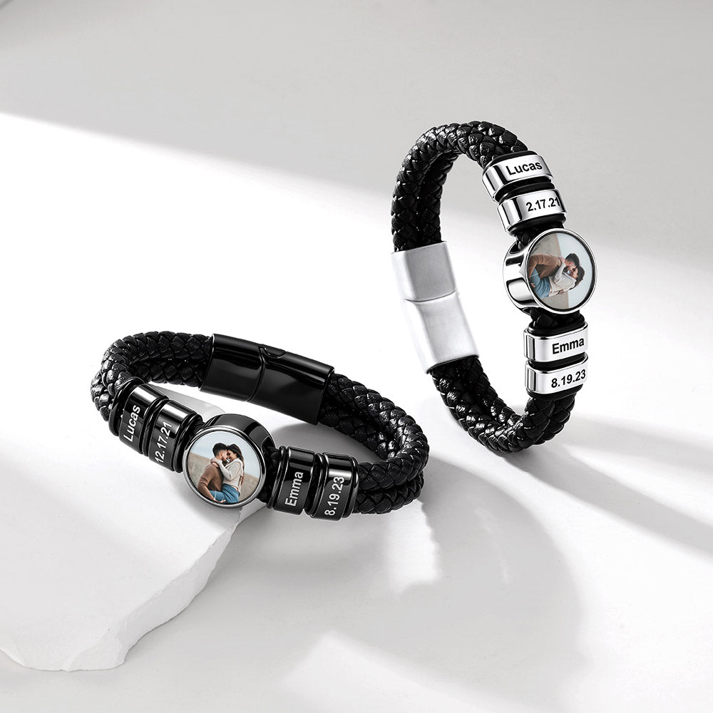 Two personalized black braided leather bracelets with silver-tone metal accents, shown on a clean white surface. Each bracelet features a round photo charm and engraved name beads.