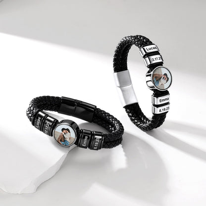 Two personalized black braided leather bracelets with silver-tone metal accents, shown on a clean white surface. Each bracelet features a round photo charm and engraved name beads.