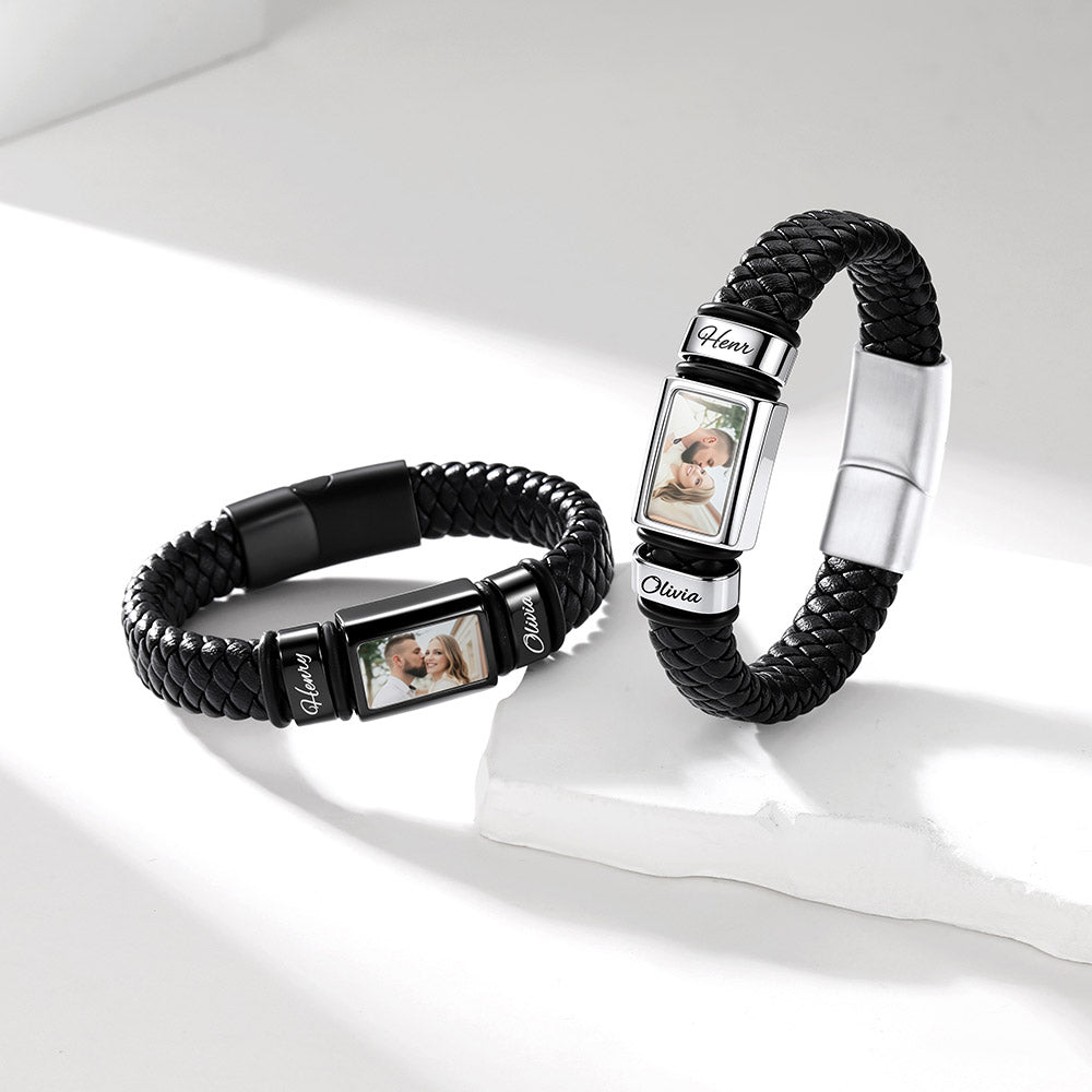Two personalized braided black custom photo leather bracelet wristlets with silver-toned photo display panels and white nameplates, arranged on a clean white surface with soft shadows.