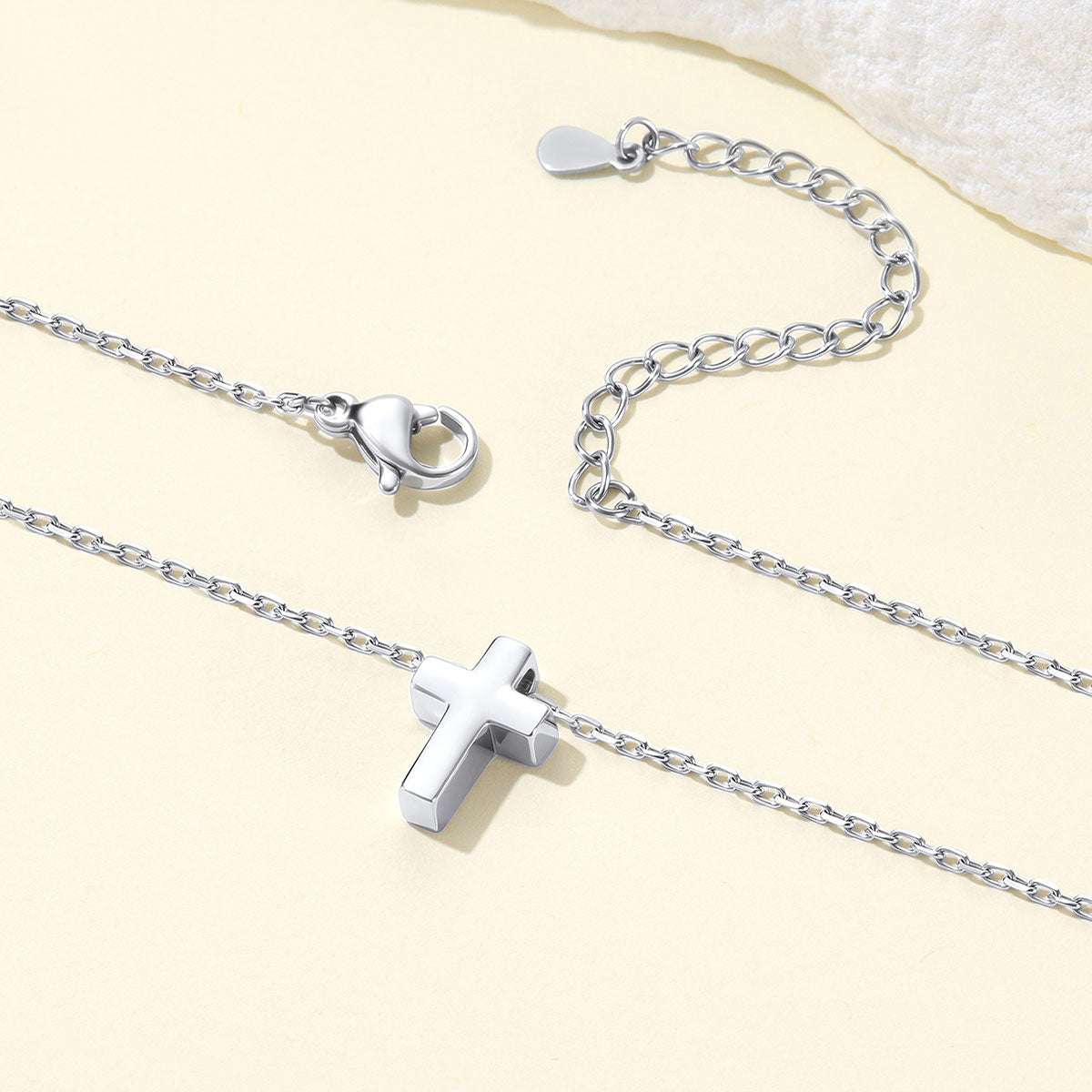 Silver cross necklace with a cross pendant on a light beige background