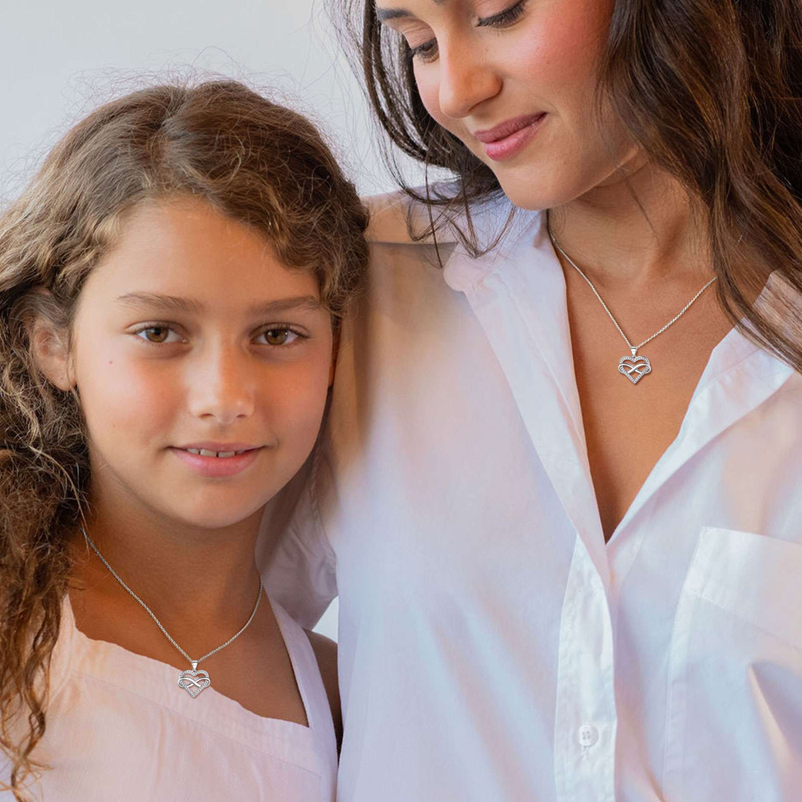 Woman and young girl wearing heart-shaped pendant necklaces 