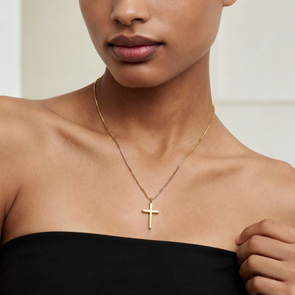 Woman wearing a gold cross necklace against a neutral background