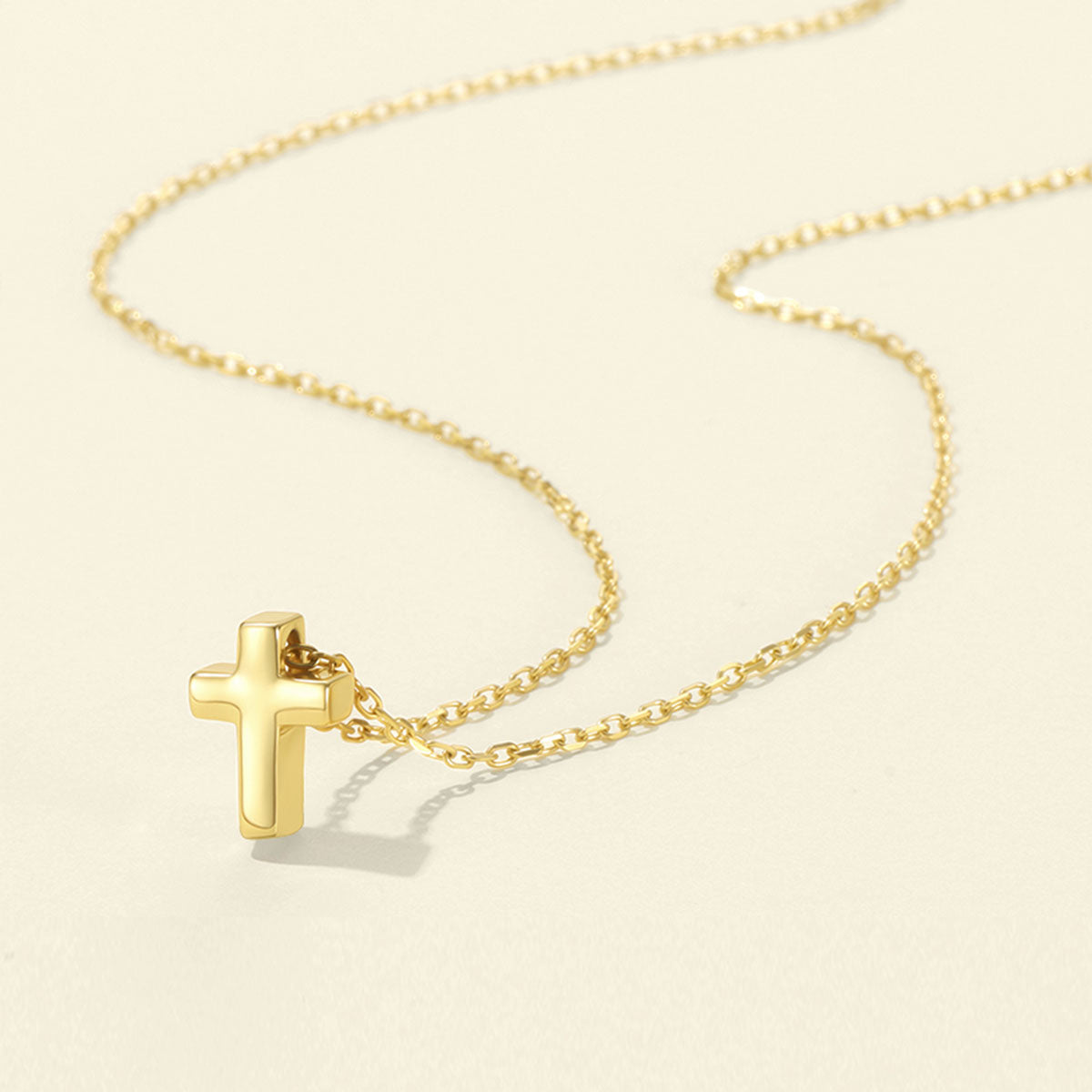 Gold cross necklace on a beige background