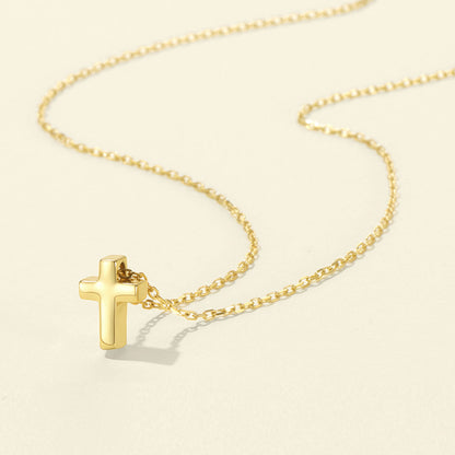Gold cross necklace on a beige background