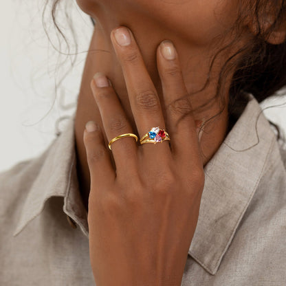 A Woman wearing a gold custom birthstone name ring and a band ring